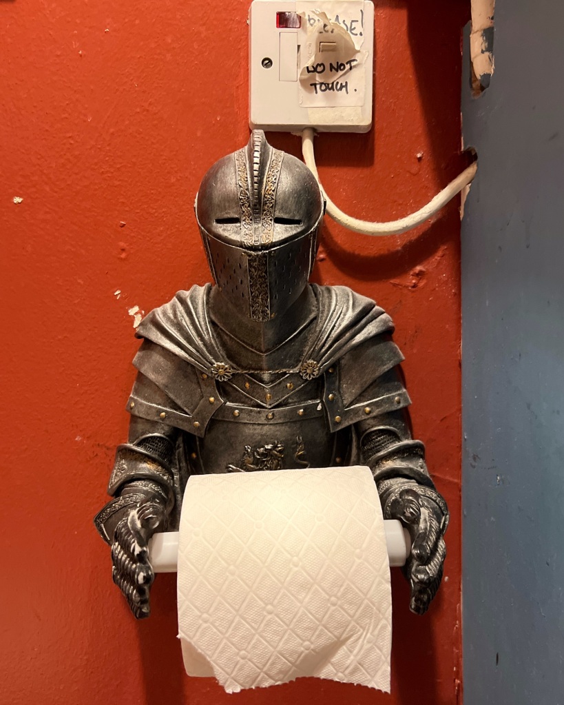 A toilet roll holder in the form of a knight in armour, with the arms holding the toilet paper roll.
